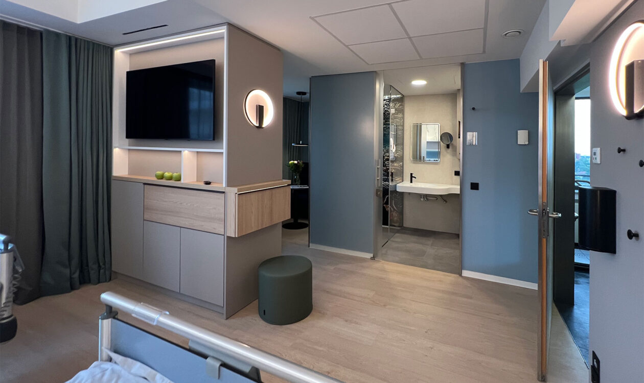Wahlleistungszimmer mit integriertem Holz-Sideboard, TV und Blick in die Nasszelle, Hospital zum Heiligen Geist Frankfurt