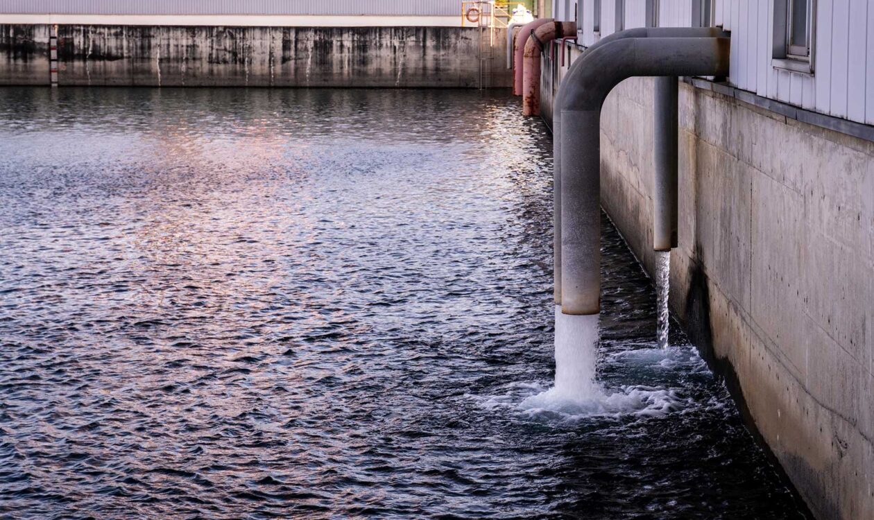 Aufbereitetes Wasser, das aus großen Industrierohre in ein Auffangbecken in einem Werk oder einer Aufbereitungsanlage geleitet wird.