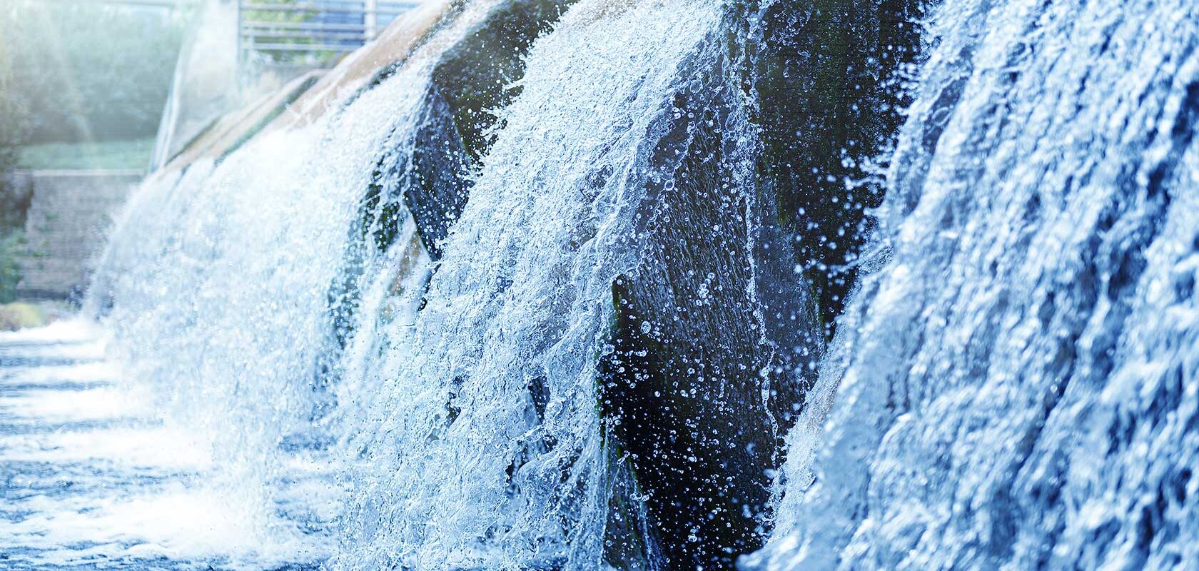 Kaltes, klares Wasser eines dekorativen künstlichen Wasserfalls