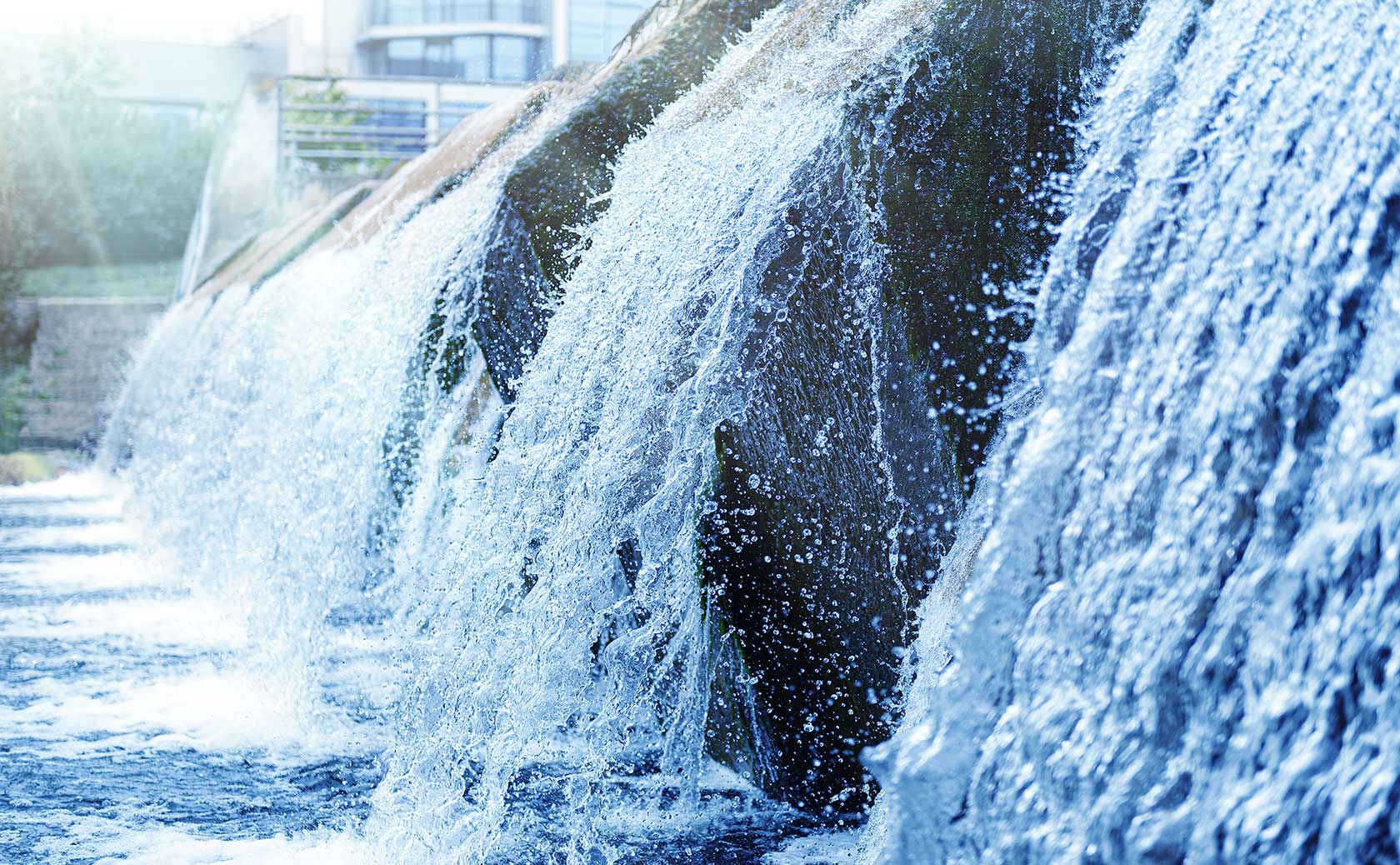 Kaltes, klares Wasser eines dekorativen künstlichen Wasserfalls